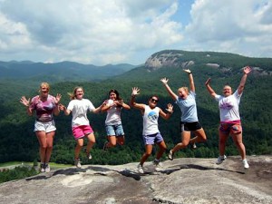 Teen campers jump on overlook rock at camp