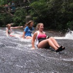 Camp girls sliding down the rock in the water