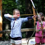Kid shooting archery at summer camp