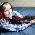Little girl camper ready to shoot rifle