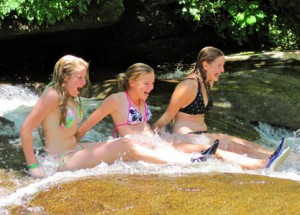 3 camp kids sliding down the rock