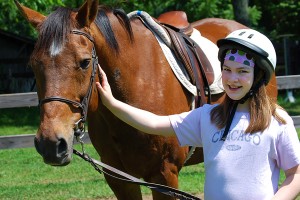 Camper girl gently caring for her horse